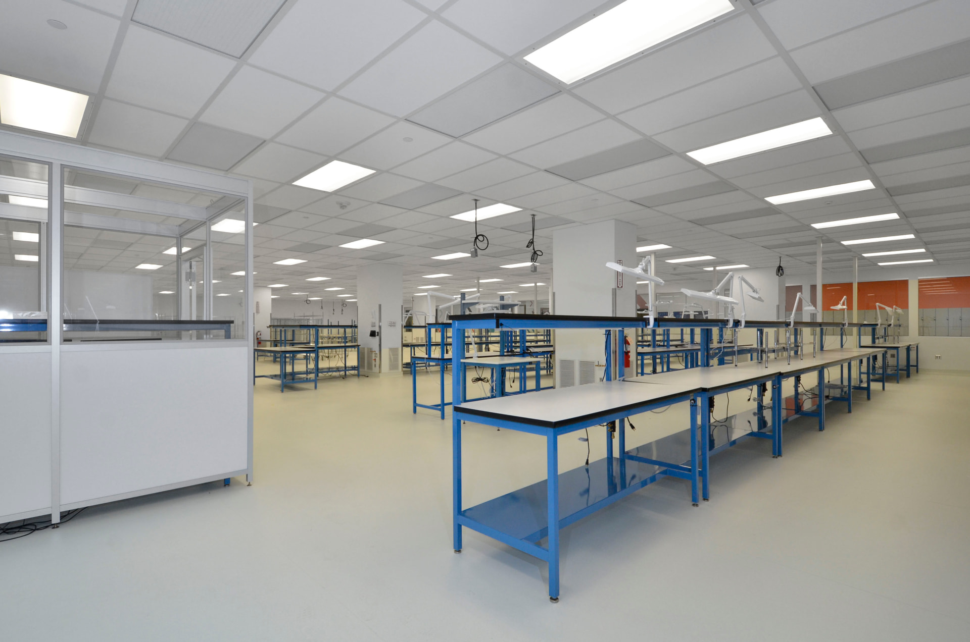 Open laboratory with rows of blue workbenches and task lighting