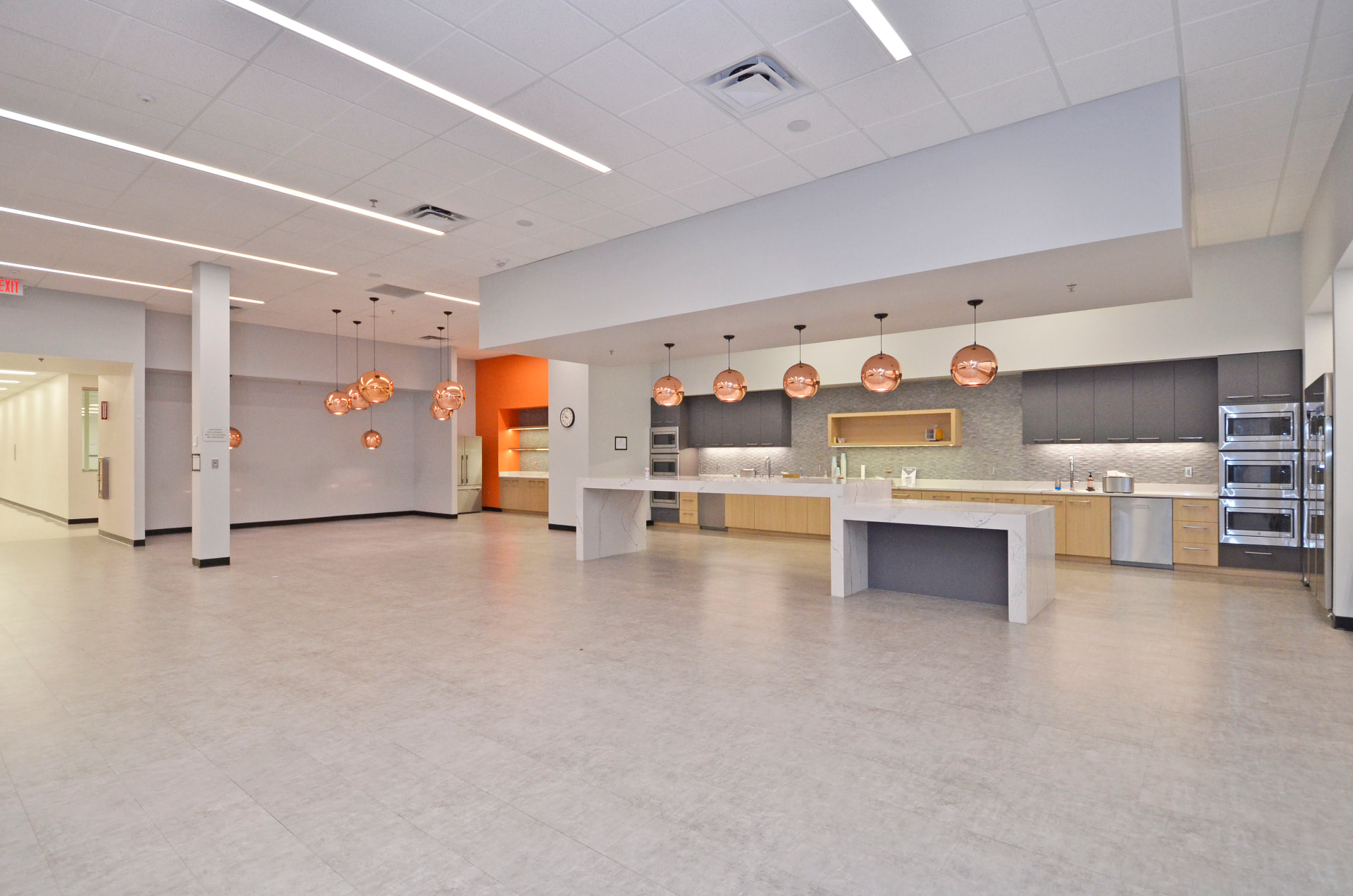 Large employee cafe with quartz islands and copper pendant lighting