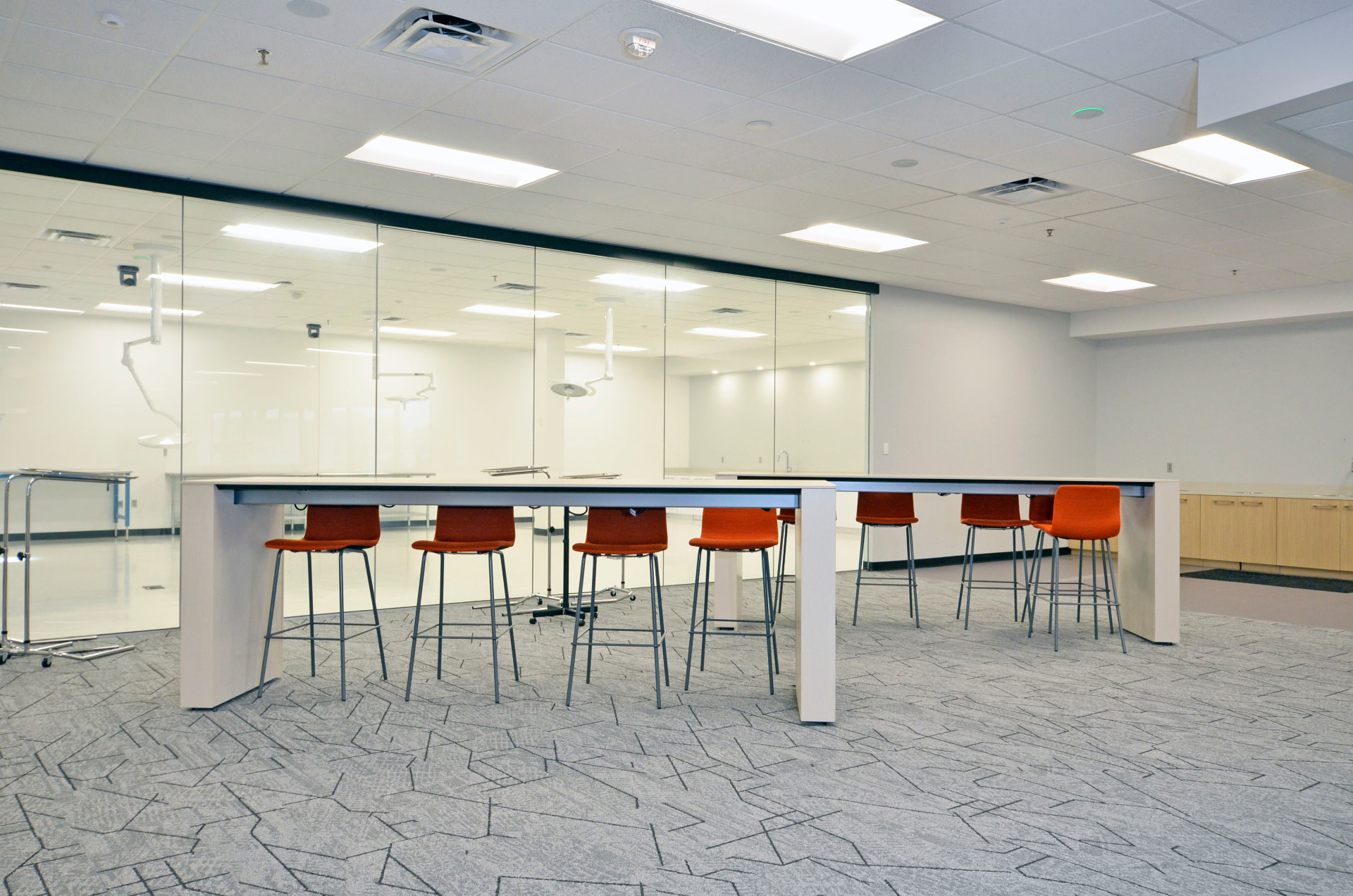 Collaboration counter with stools beside a glass lab wall